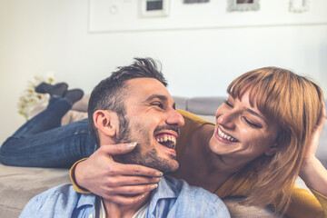 Young couple spending time together at home. Man and woman sitting on the couch and having fun.