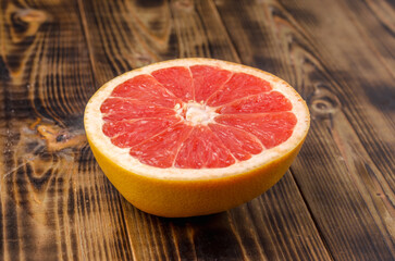 Cut grapefruit half on wooden table.