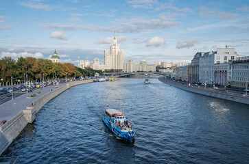 Naklejka premium Moscow in summer. View from Moskvoretskaya embankment to the high-rise on Kotelnicheskaya embankment. Pleasure boat on the Moscow River.