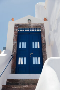 Beautiful blue door on white facade of greek architecture in Oia city, Santorini island, Greece, Europe. Beautiful details of the island of Santorini. Famous travel destination with blue sky view