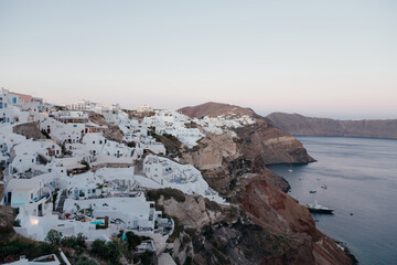 View of Oia town with view on the sea on sunset time in Santorini island, Greece. Summer vacation and holiday concept, luxury travel. Wonderful scenery, cruise ships and white architecture