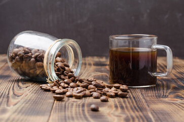 Cup of coffee and beans are scattered from a glass jar.