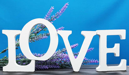 Word LOVE from letters on a blue background with lavender flowers