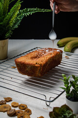 Icing sugar being drizzled over a freshly baked Banana Bread Loaf.