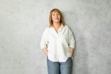 Portrait of mature woman with red hair smiling on gray background. Professional businesswoman on grey