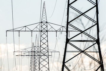 A line of electricity pylons against a blue morning sky