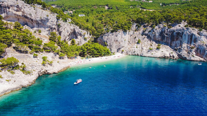 This is a beautiful coastal beach in Makarska, Croatia. The turquoise waters embrace the sun-kissed sand and the powerful waves crashing against the shore offer a peaceful escape from the busy world. - obrazy, fototapety, plakaty