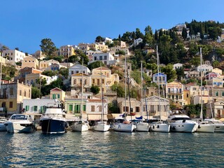 Fototapeta na wymiar Symi island view from the sea. Aegean Sea. Marina, yachts, colourful houses, mountain. Boats in the harbor. Greece. Dodecanese islands 