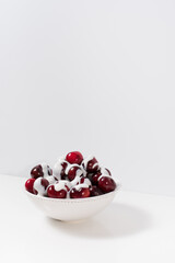 Cerezas dulces rojas con crema de yogurt en un recipiente blanco y fondo claro