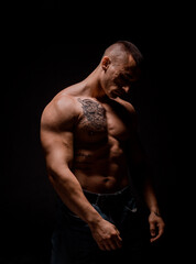 Fototapeta premium Man posing and showing his arm muscles while posing on black background