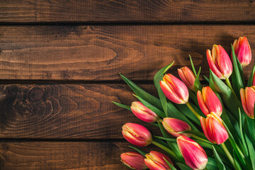 A bouquet of tulips lies on a brown wooden background