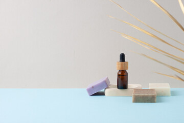 Cosmetic bottle with soap and palm leaf on grey, blue background. Close up, copy space