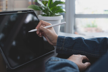 Close up of business woman hand using stylus pen touching on digital tablet screen, working at home...