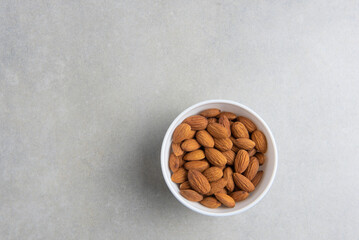 almonds in a white cup on a concrete background. concept for a recipe for making almond flour. top view