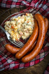 Thin sausages with vegetable salad on plate.