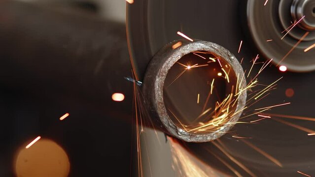 Closeup of how round piece is cut off from metal hollow pipe using cutting disc and an angle grinder. Artisan cuts piece from tin pipe using an angle grinder
