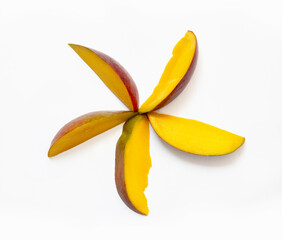 Top view slices of fresh mango fruit lie in the shape of a star or flower, isolated on a white background