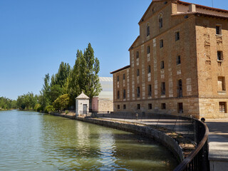 Fototapeta na wymiar Dock of Canal de Castilla in Medina de Rioseco, with the building of the old San Antonio flour mill. Province of Valladolid, Castilla y León, Spain. Civil engineering waterway of the 18th century