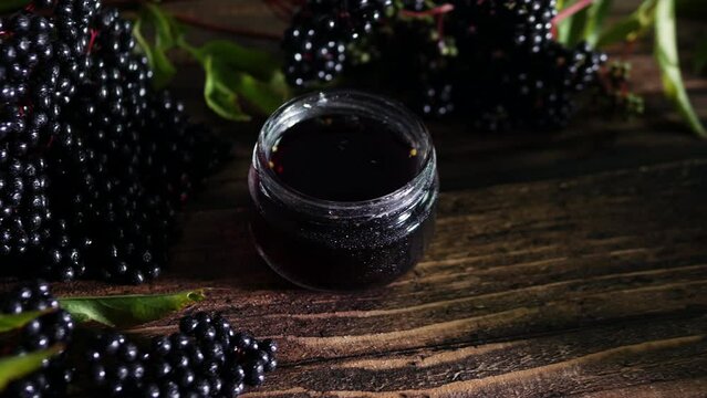 Natural black elderberry on a wooden table, red freshly squeezed juice from the berry.