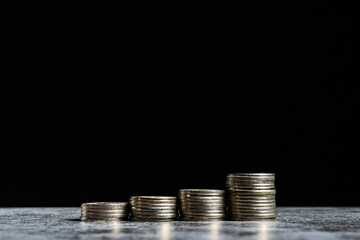 Stacks of coins on grey table and black background like growth financial symbol