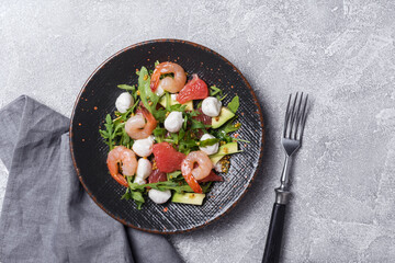 Healthy salad with fresh arugula, mozzarella cheese, tasty shrimps, grapefruit and avocado