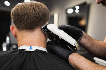 Barber cutting a man's hair with a clipper. Haircut process in salon.