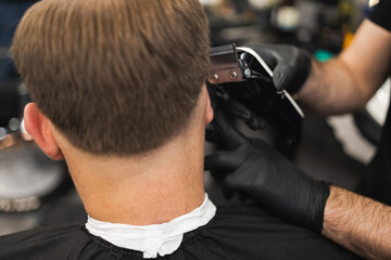 Close-up of a hairdresser cutting a client's hair with a electric clipper