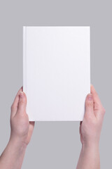 mockup of a white hardcover book cover in hands. Applicable for design presentation