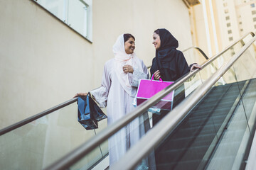 Two arabian girls spending time together outdoor making activities. Young women making shopping in Dubai