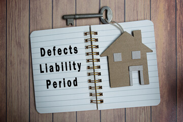 Defects liability period text on notepad with house model and key on wooden desk