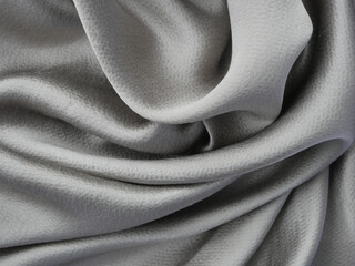 Gray silk beautiful fabric, folded in careless folds. Smooth waves of silk fabric - abstract background, modern image.