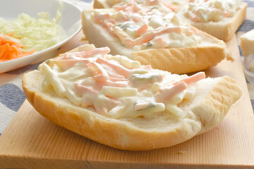 Creamy coleslaw sandwich on a bamboo cutting board. 