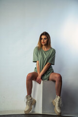 Concept close-up portrait of a pretty girl, young woman with long beautiful brown hair in a green t-shirt on a white background. In the studio in different poses showing emotions