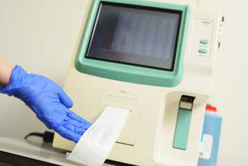 a laboratory assistant examines a blood sample in an analyzer in a modern microbiological clinic.