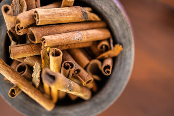 Wooden bowl top view with cinnamon sticks on dark wooden background. Abstract food and cooking ingredients for dessert and healthy meals
