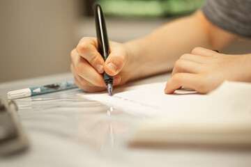 junge schreibt mit einem Füllfederhalter, der Hand ein Notizbuch hält