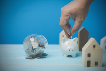 A man saves money to keep in a white piggy bank to buy and invest business property. house trading...