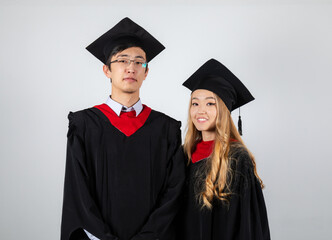 Graduates couple in gowns posing together on white background