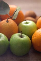 Pineapple, apples, oranges, lemons and kiwis on a wooden table. Selective focus.