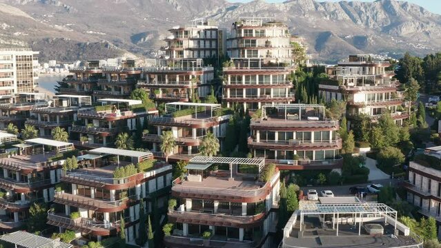 Luxury apartment buildings on the hillside - homes with view. Residences in a vacation tourist destination on the Mediterranean sea coast. Rooftops of green eco houses - aerial drone view on sunny day