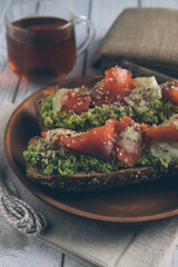 Bruschetta with salmon and avocado on a wooden plate on a white wooden background.