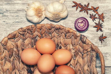 Background with spices, garlic, anise and chicken eggs in a wicker basket