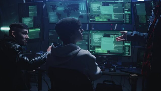 Group of hackers near monitors communicating nervously during cybercrime massive cyber attack. They quarrel and argue