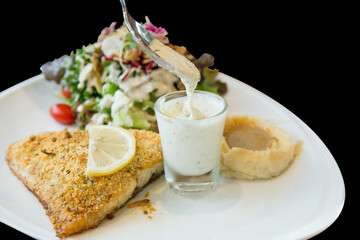 Die cut of Grilled Sea Bass Steak with Salad on black isolated