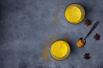 Top view two glasses of healthy and tasty golden milk made from turmeric powder. Traditional...