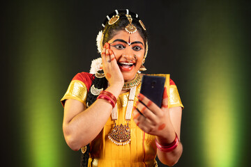 excited Bharatnatyam dancer by seeing as winner on mobile phone - concept of online shopping e-commerce offers, final round selection and technology