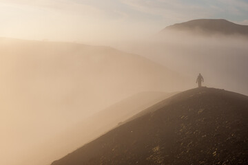 A person walking in fog during sunrise in the Veiðivötn lake area, Central Highlands of Iceland. Moody warm light.