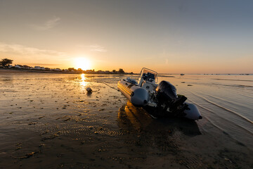 Bateau semi-rigide pour la pêche de loisir côtière posé sur le sable à marée basse au soleil...