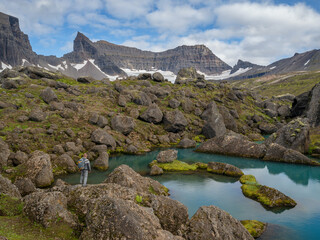 A hiker enjoying the view at Stórurð boulders, East Iceland. Mount Dyrfjöll in background.