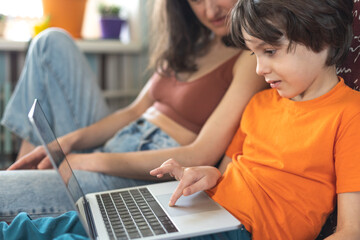 a woman with a child is sitting at a laptop